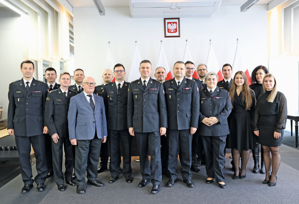 Biuro Przeciwdziałania Zagrożeniom: w centralnej części zdjęcia dyrektor biura st. bryg. Ernest Ziębaczewski, po jego prawej stronie zastępca dyrektora st. bryg. Rafał Szczypta; pracownicy biura począwszy o lewej strony: st. bryg. Sławomir Zając, st. kpt. Kamil Wleciał, mł. bryg. Radosław Czapla, st. bryg. Dariusz Dziwulski, st. bryg. w st. sp. dr inż. Dariusz Ratajczak, kpt. Grzegorz Sobieszek, bryg. Karol Mojski, st. bryg. Paweł Rochala, st. kpt. Artur Kądziela, mł. bryg. Wojciech Wiśniewski, st. bryg. Ariadna Koniuch, kpt. Oliwer Eszer, Natalia Galas, Grażyna Markevičius, Michalina Musiał. Na zdjęciu brakuje bryg. Konrada Leszczuka, mł. bryg. Agnieszki Czyżewskiej, kpt. Renaty Golly, st. bryg. w st. sp. mgr. inż. Piotra Wojtaszewskiego / fot. Anna Sobótka / red. PP