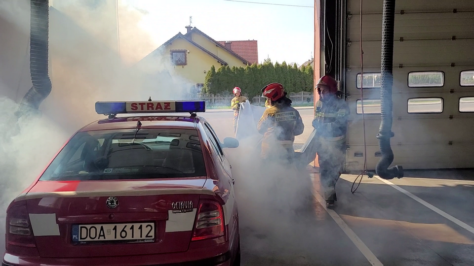 Nakładanie płachty na pojazd zaparkowany w garażu JRG Oława. Zadymienie symulowano za pomocą dymu teatralnego fot. arch. JRG Oława
