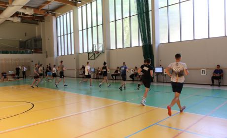 Trwa sprawdzian sparwności fizycznej. Klika osób biegnie na czas w sali sportowej.