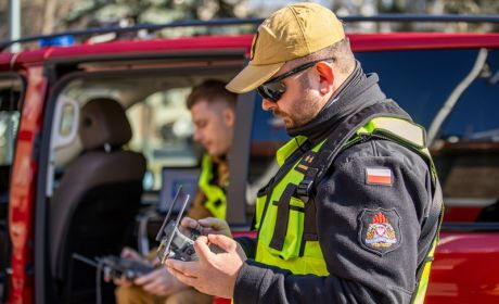Strażak trzyma w rękach pilot do sterowania dronem. 