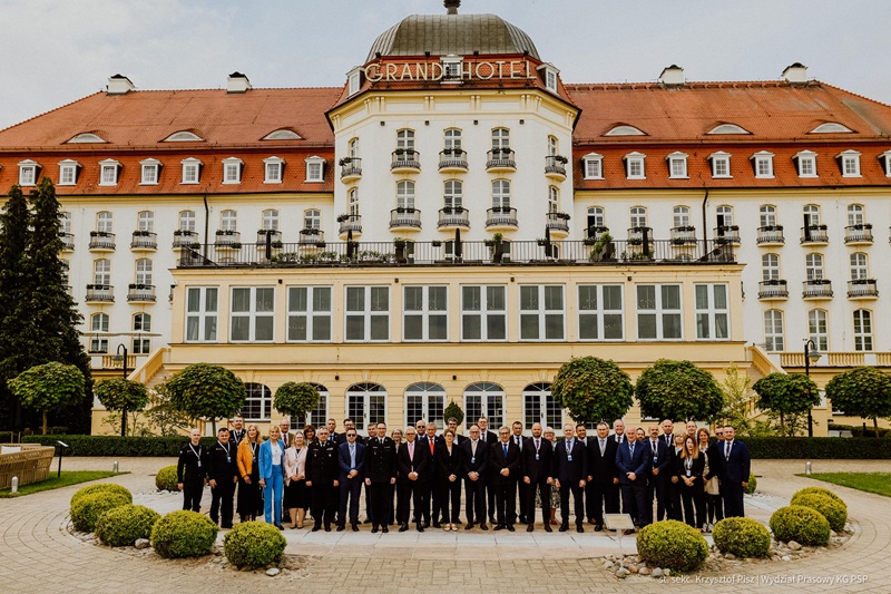 Grupa osób pozuje do zdjęcia przed hotelem.