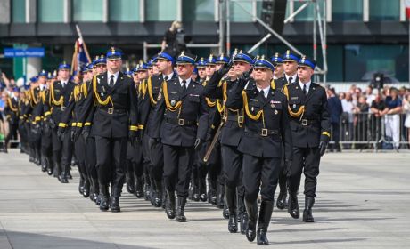 Przemarsza kompanii. Strażacy w mundurach galowych maszerują. Kilku strażaków salutuje.