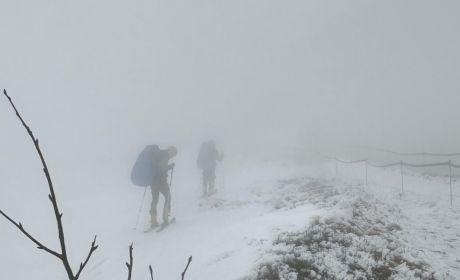 Zima, wszędzie widać leżący śnieg. Dwóch mężczyzn wchodzi pod górę. Na nogach mają załozone narty. W rękach trzymają kijki.Na plecach dźwigaja niebieskie plecaki. 