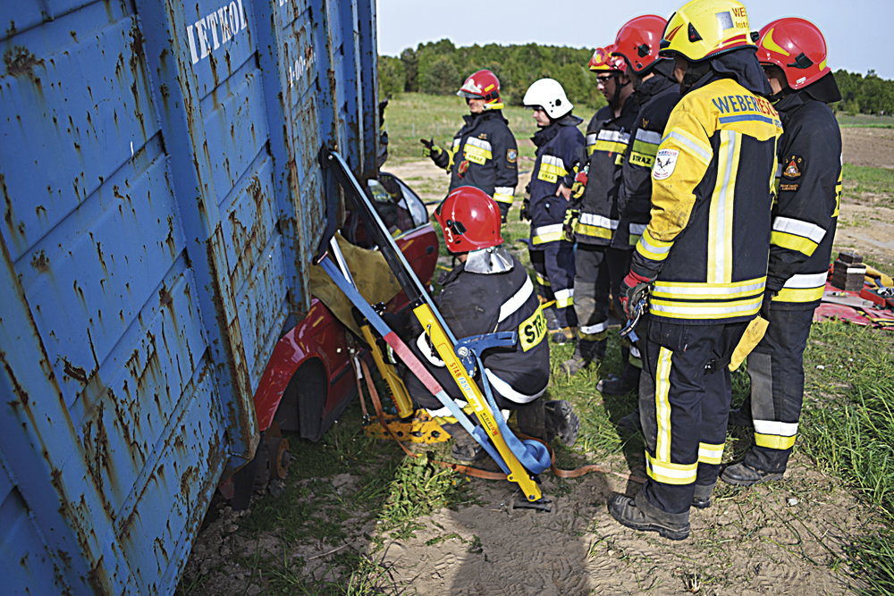 Fot 12. Stabilizacja boczna kontenera i jego wstępne unoszenie rozpieraczami kolumnowymi, osadzonymi na wspornikach progowych, połączonych pasem transportowym