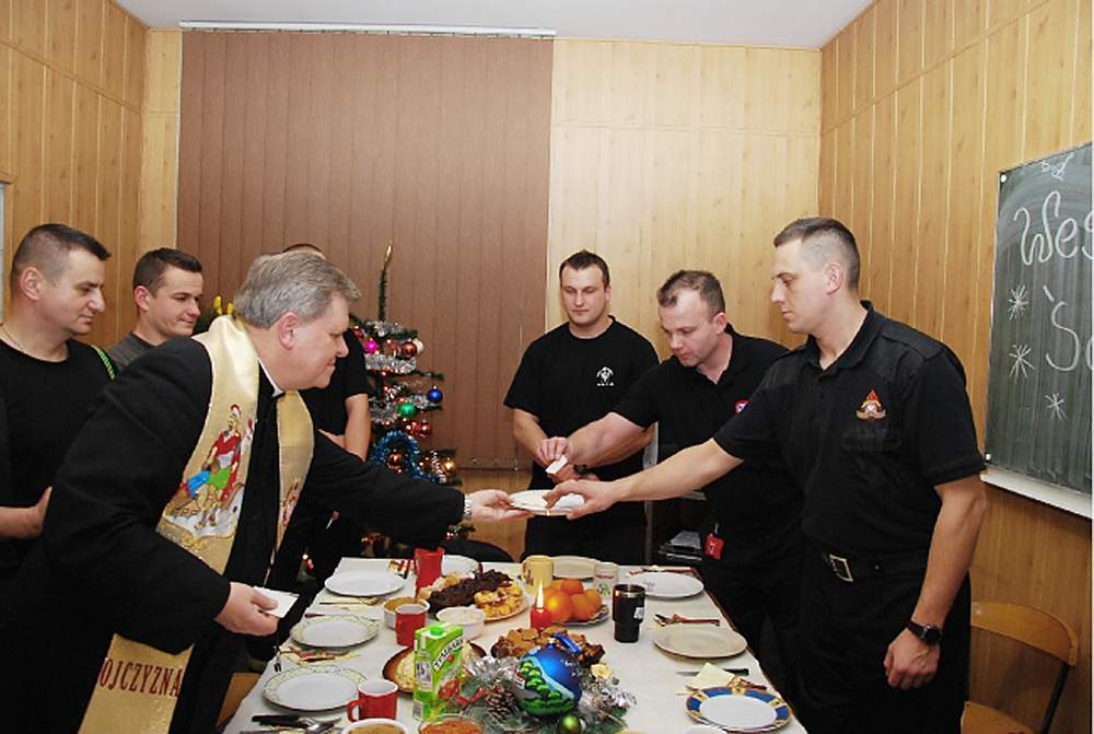 Fot. 3 Jeleniogórscy strażacy, którym wypadła służba w święta, dzielą się opłatkiem z ks. Grzegorzem Niwczykiem, fot. archiwum KM PSP w Jeleniej Górze